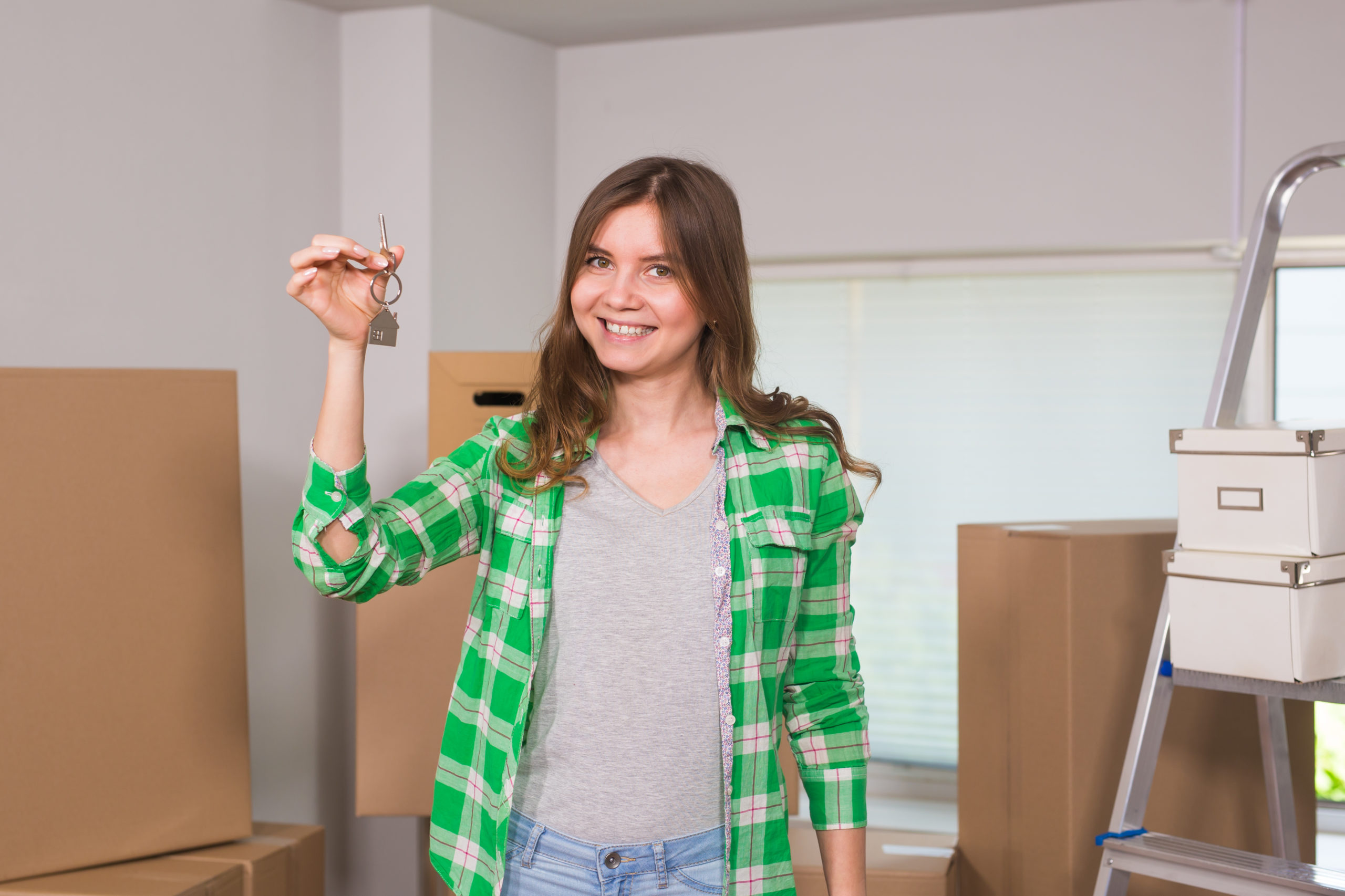 Happy apartment owner or renter showing keys and making thumbs up gesture.